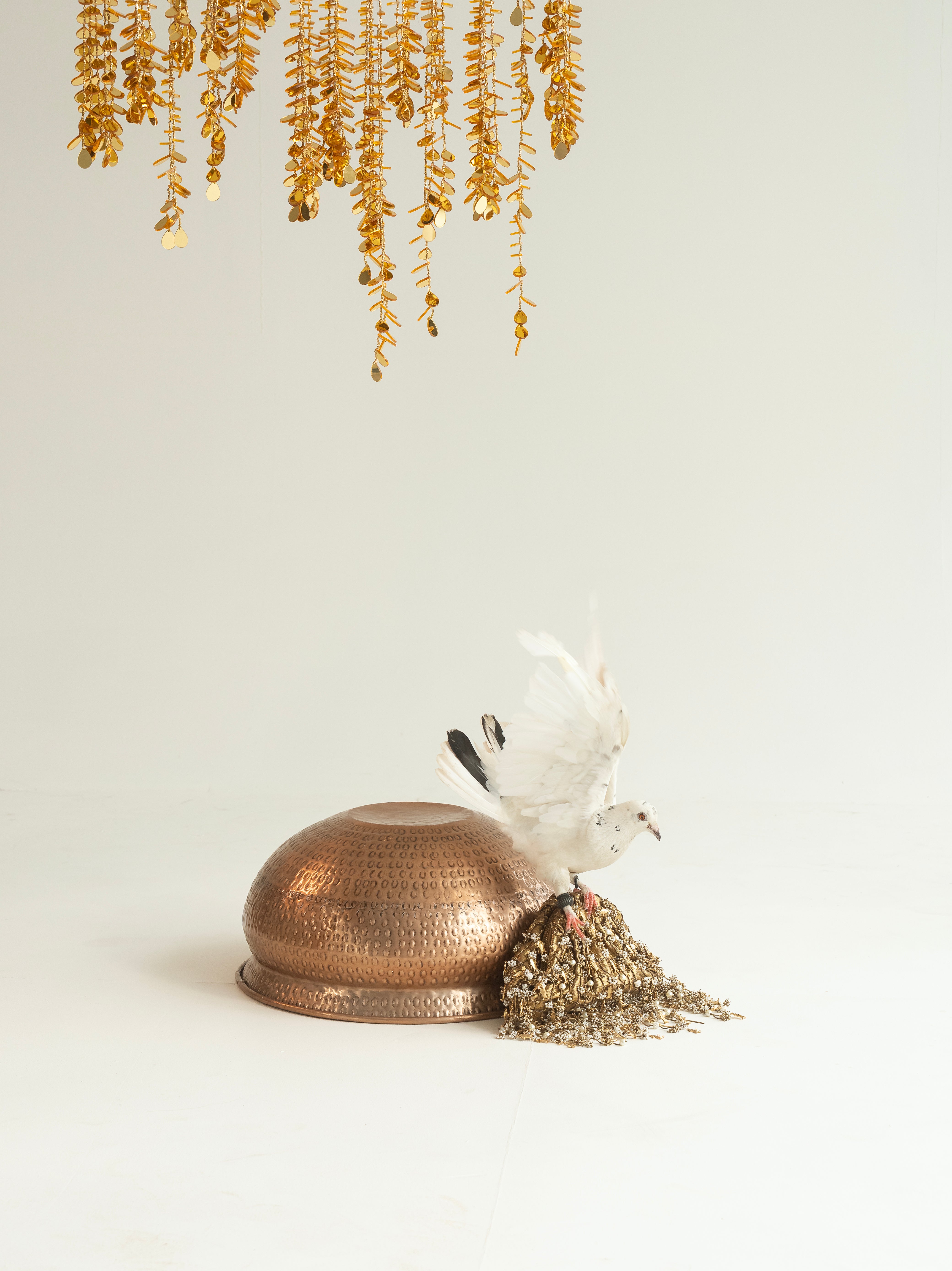 Gold-toned hanging garlands with copper bowl and white dove – luxury Indian wedding décor by Amama