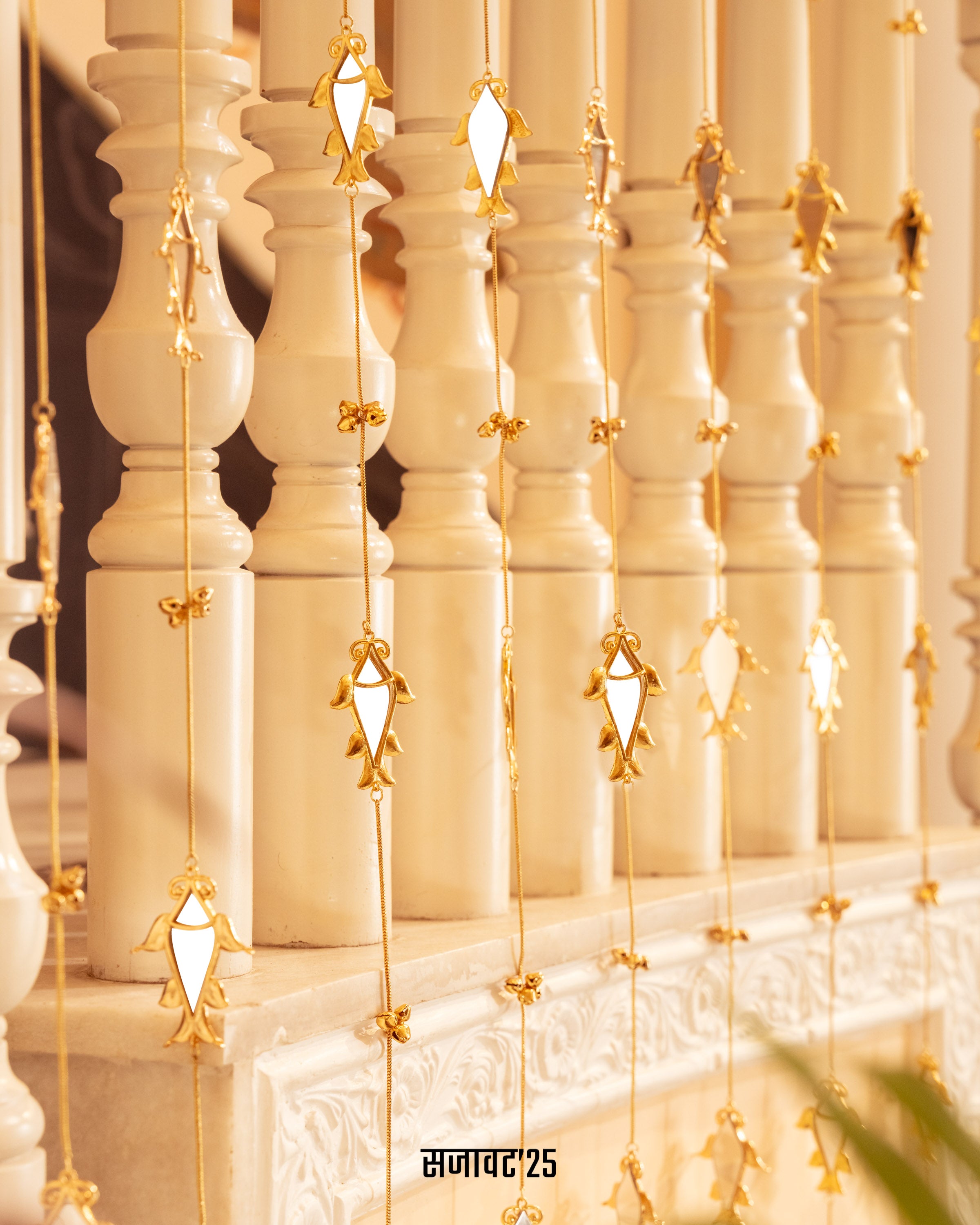 Decorative string lights with gold accents hanging against a white wall.
