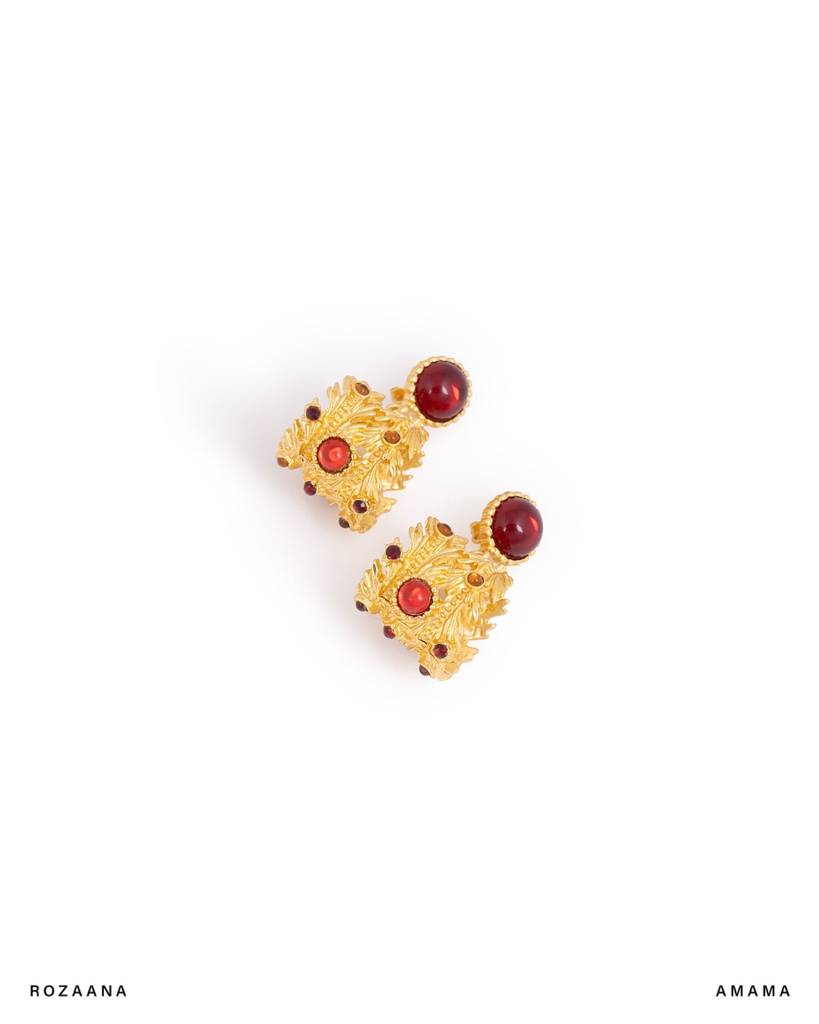 Pair of gold earrings with red stones on a white background
