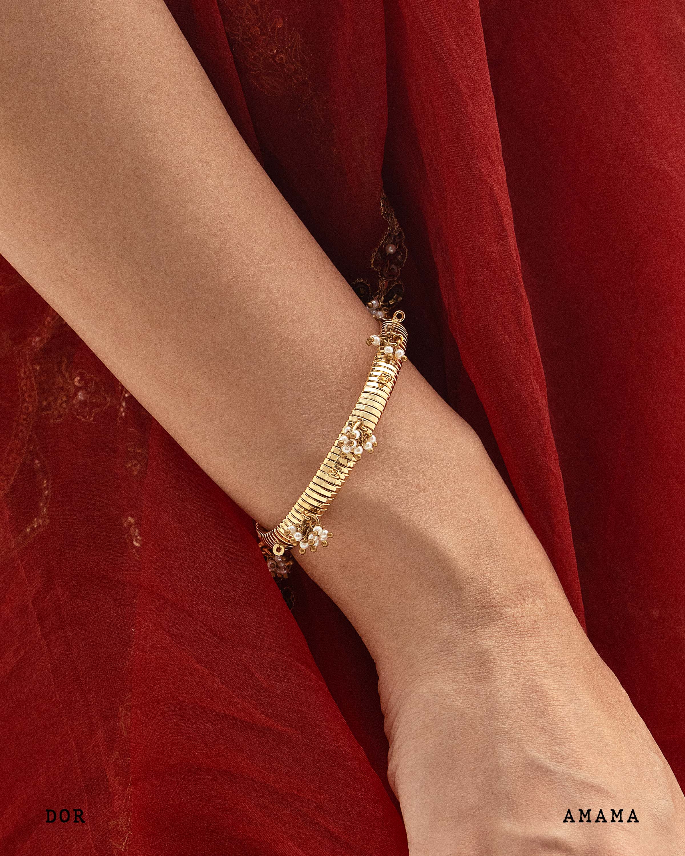 Gold bracelet on a wrist with a red fabric background