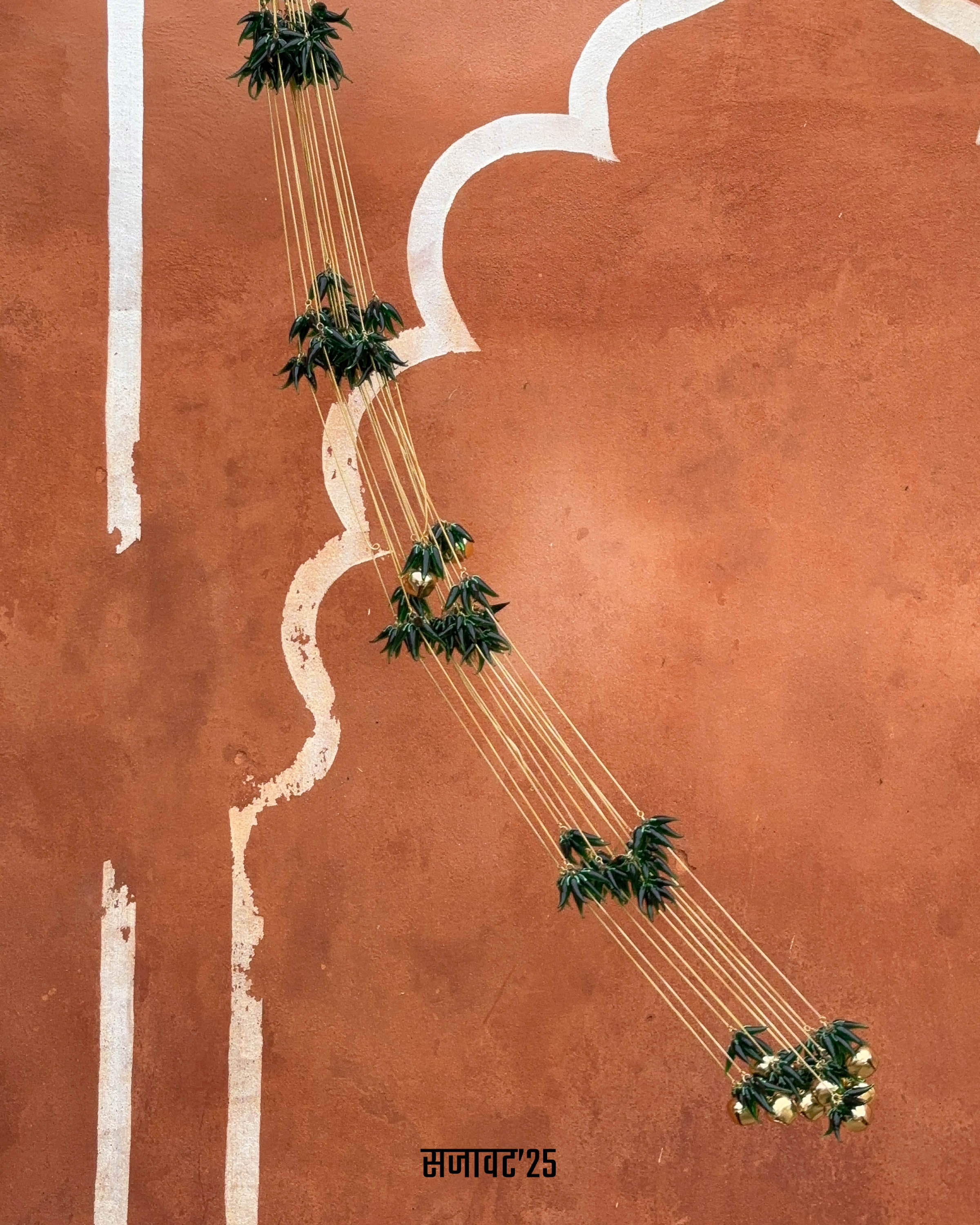 Decorative string with green leaves and gold balls hanging against a window.