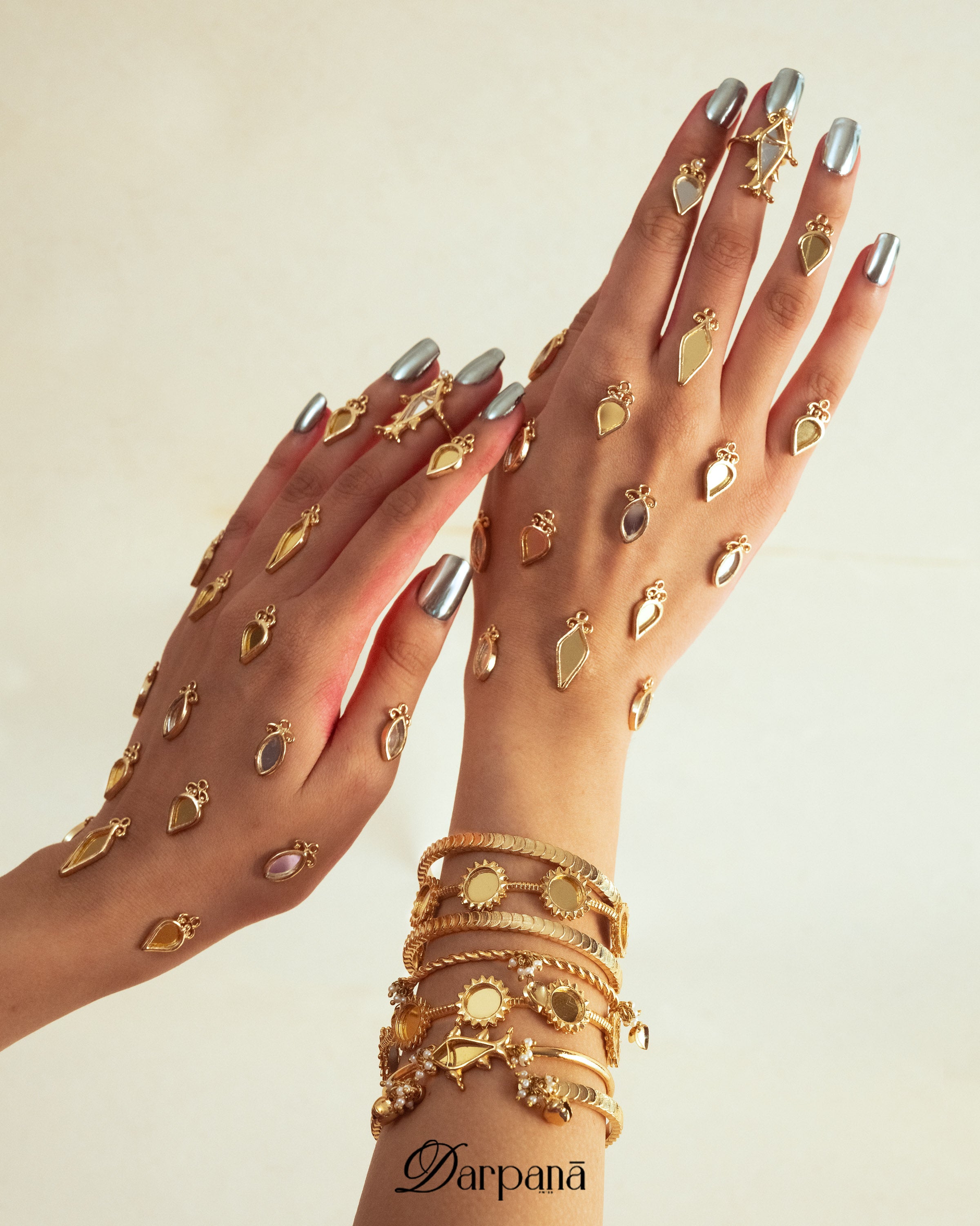 Gold jewelry set on hands with 'Darpana' brand nam
