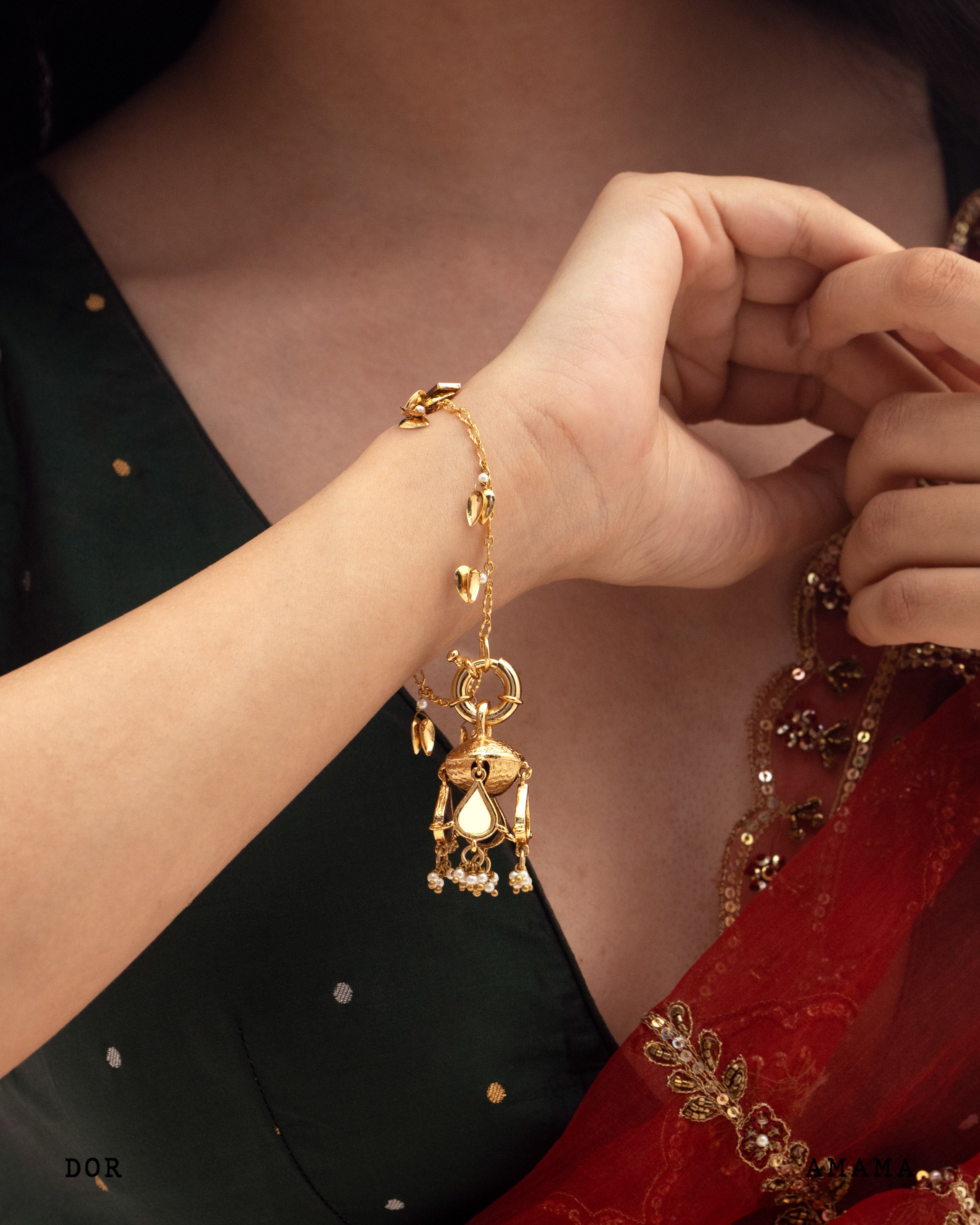 Gold bracelet with a pendant worn on a wrist, with a blurred background