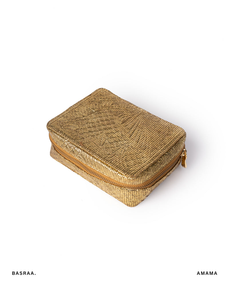 A closed, textured gold-colored jewellery box with the brand name 'BASRAA' and the word 'AMAMA' on the bottom right corner.