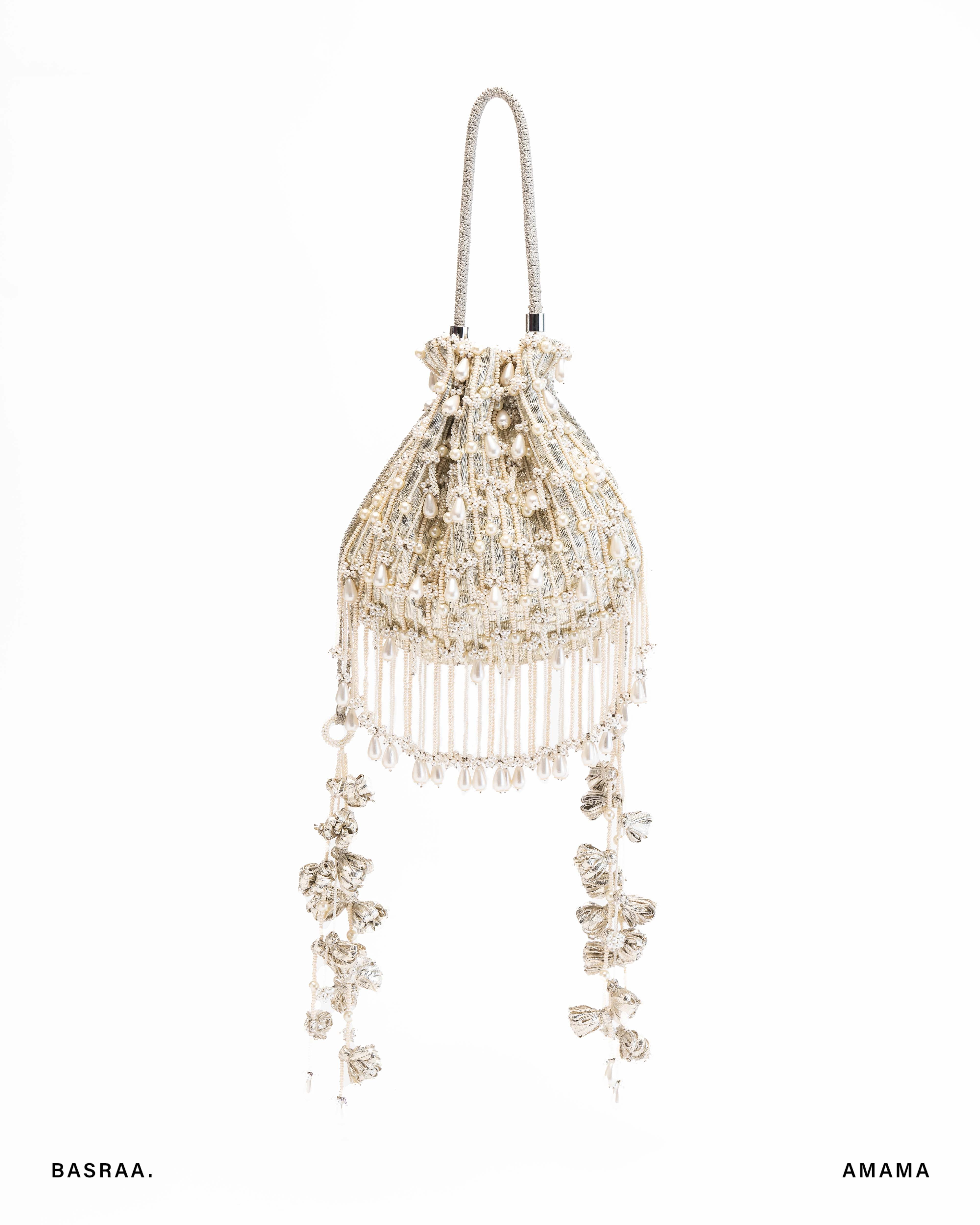 A silver-colored Basra pearl potli with intricate hand-embroidered designs and pearl-like bead details, featuring a hanging tassel.
