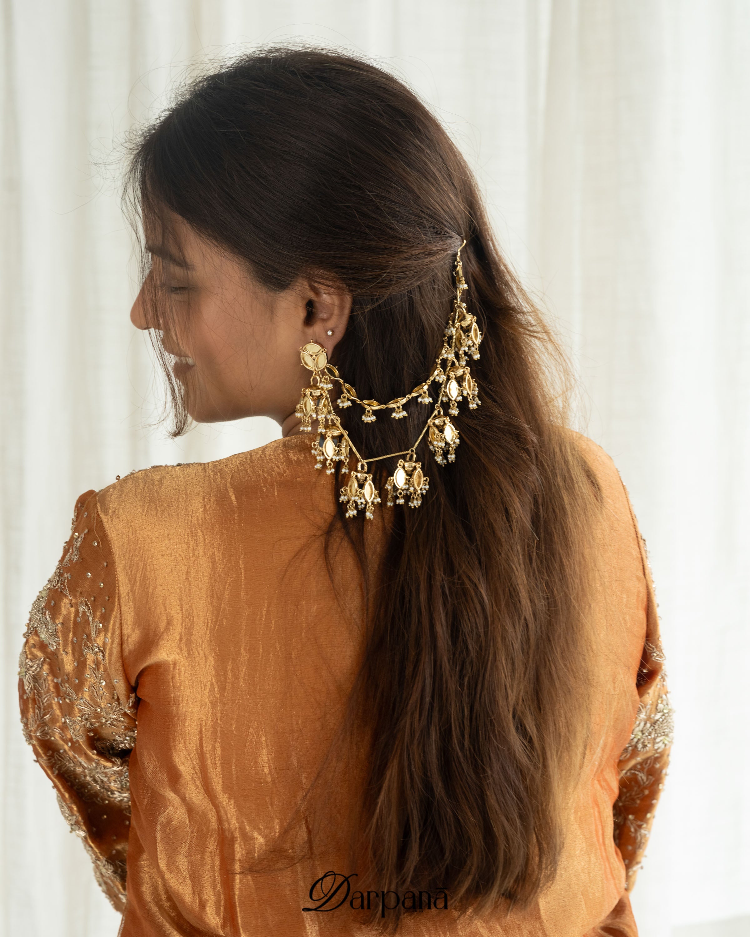 Woman wearing gold earrings with a plain background