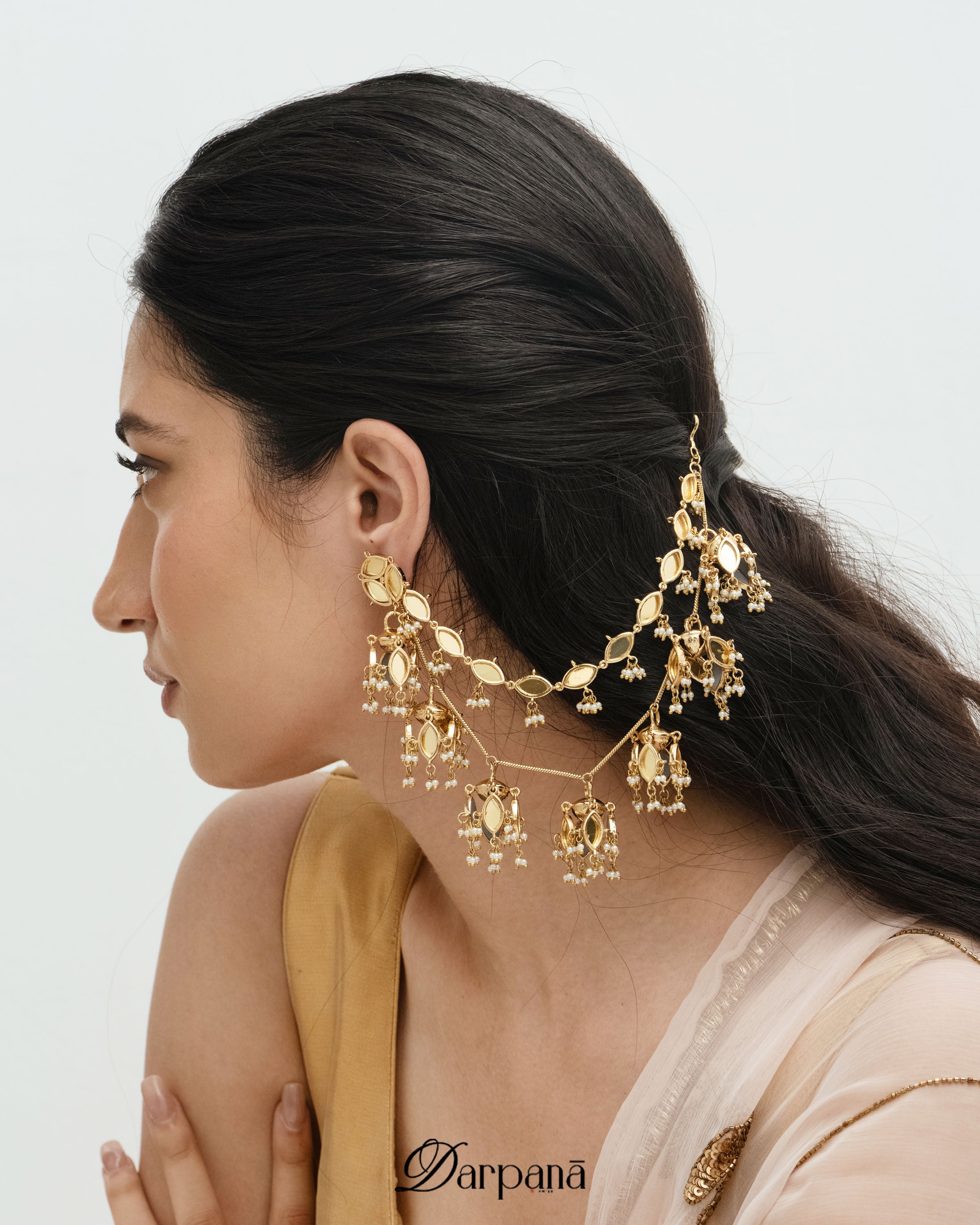 Woman wearing gold earrings with a plain background