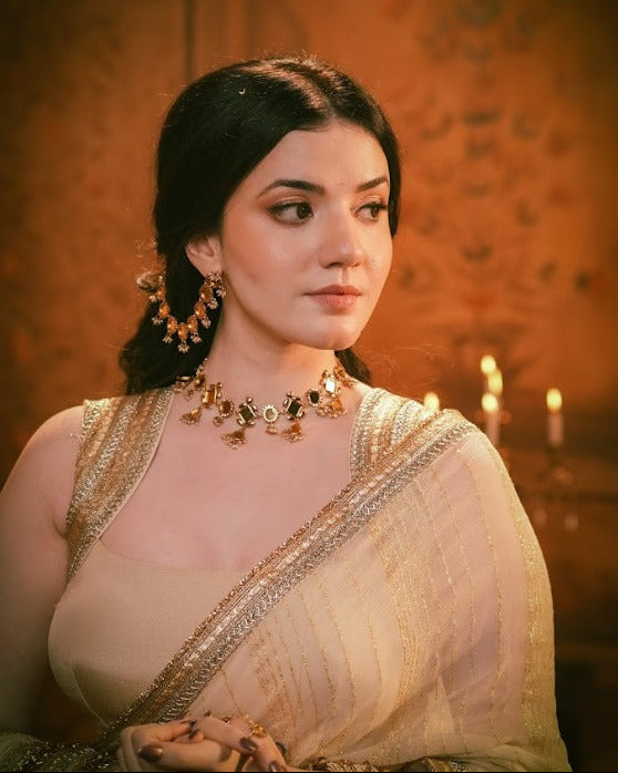 Woman in traditional attire with jewelry against a warm-toned background