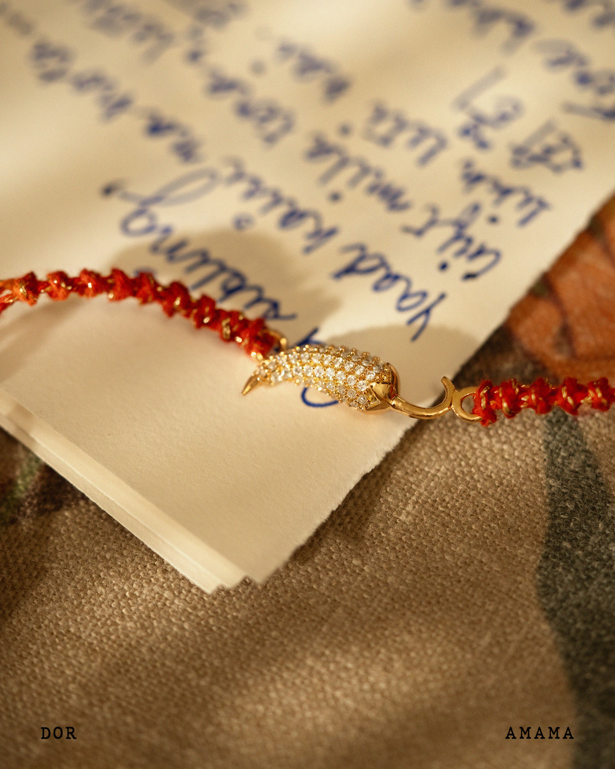 Bracelet with red beads and gold charm on a piece of paper with writing