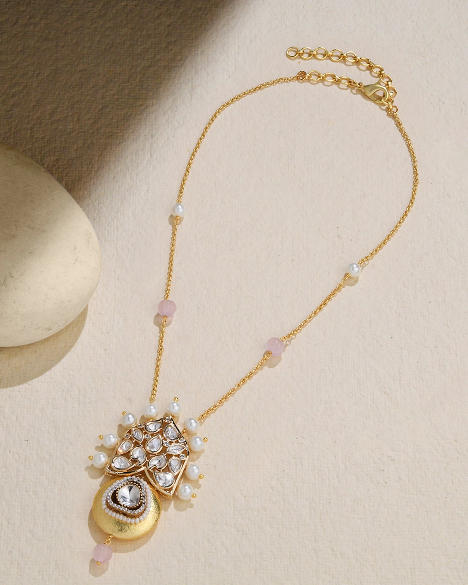 golden necklace featuring a pendant with a pearl
