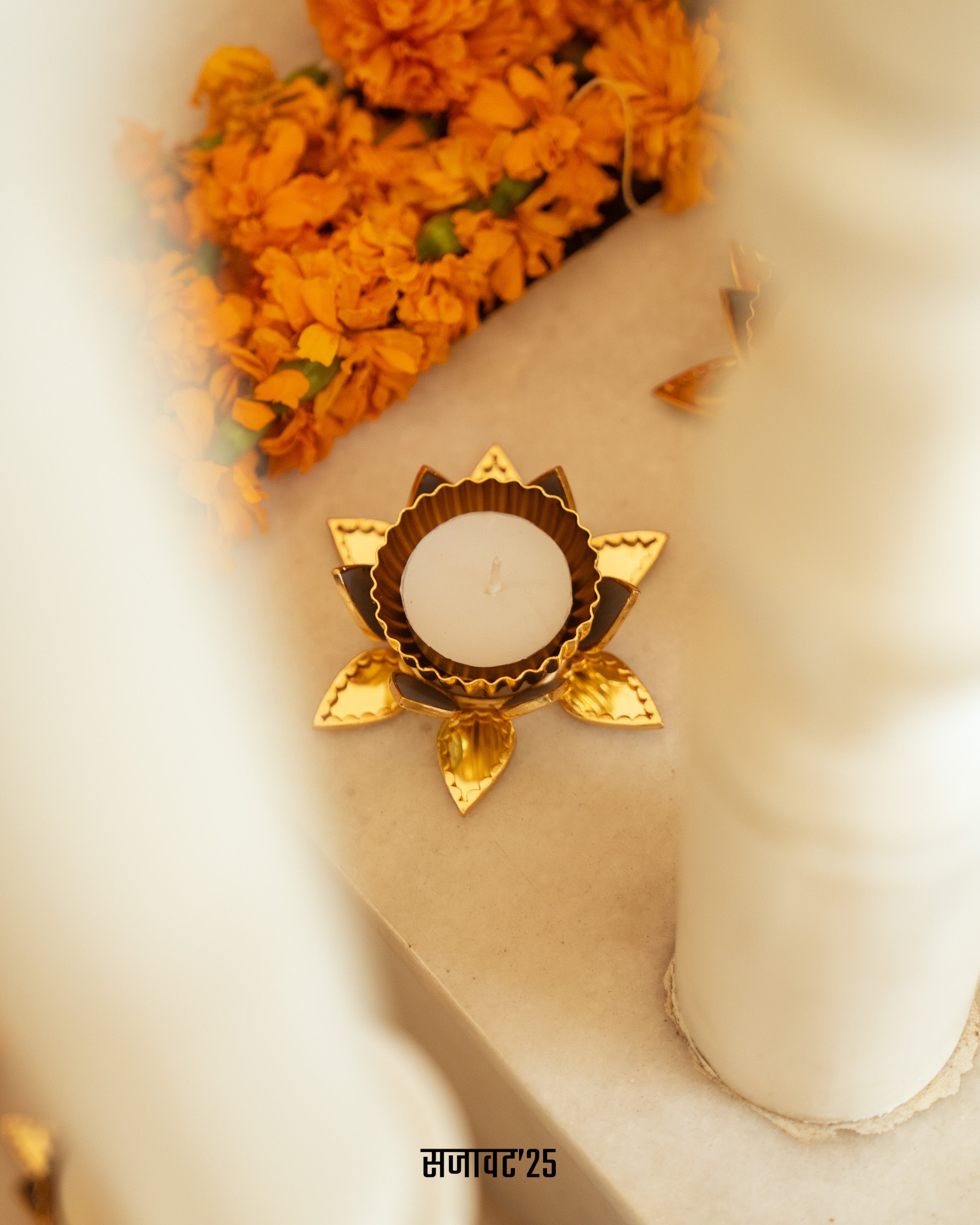 Decorative gold candle holder with marigold flowers on a white surface

