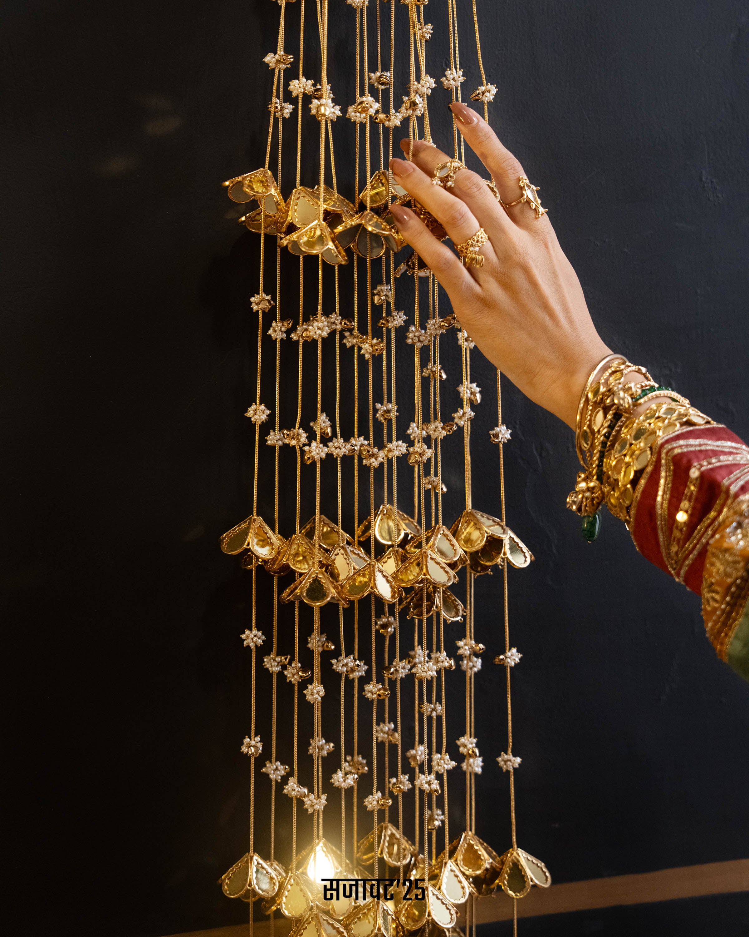 Hand holding a gold wind chime against a dark background