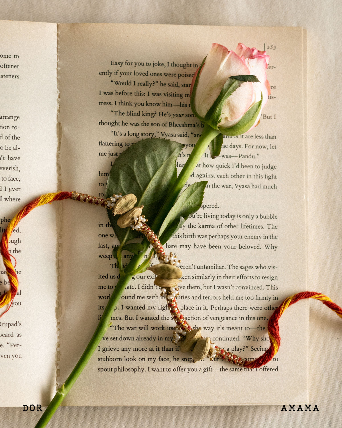 Decorative elements on an open book with a pink rose and colorful beads.