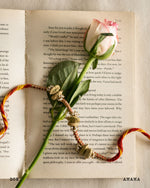 Decorative elements on an open book with a pink rose and colorful beads.