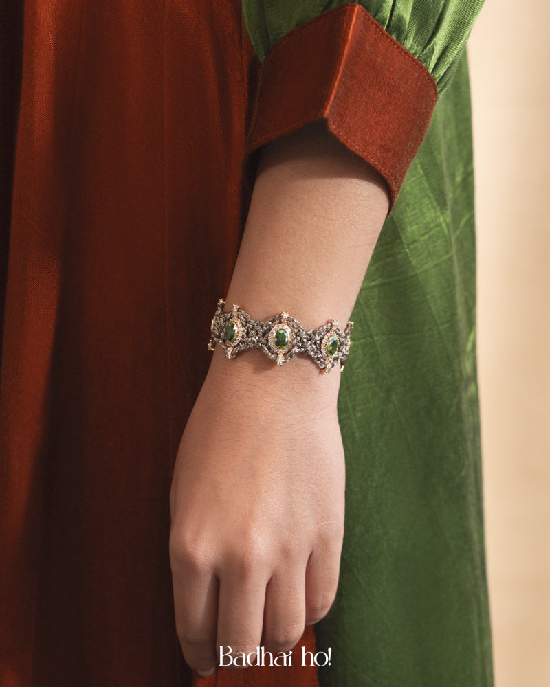 Bracelet with green gemstones on a wrist, against a blurred background

