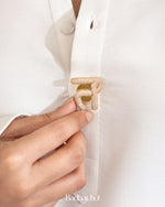 Close-up of a hand adjusting a gold brooch on a white shirt with 'Badhai Ho' branding.

