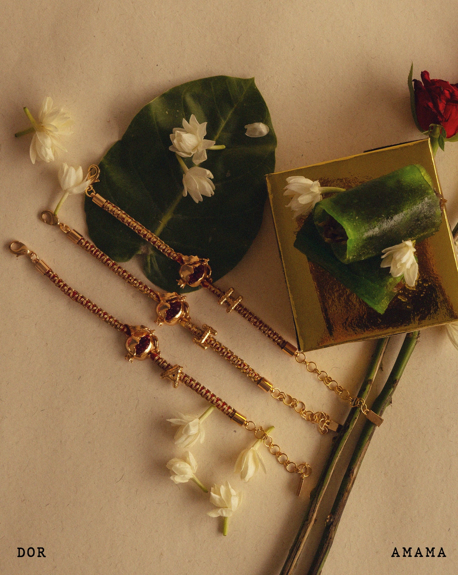 A collection of golden and silver-colored Rakhis, traditional Indian wristbands, presented alongside flowers and leaves on a beige background.