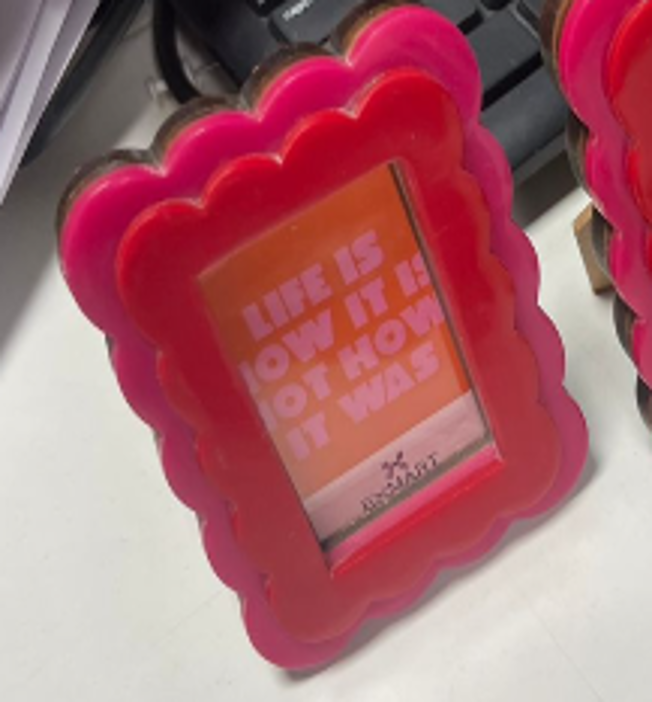 Pink scalloped photo frame with a motivational quote on an orange background.