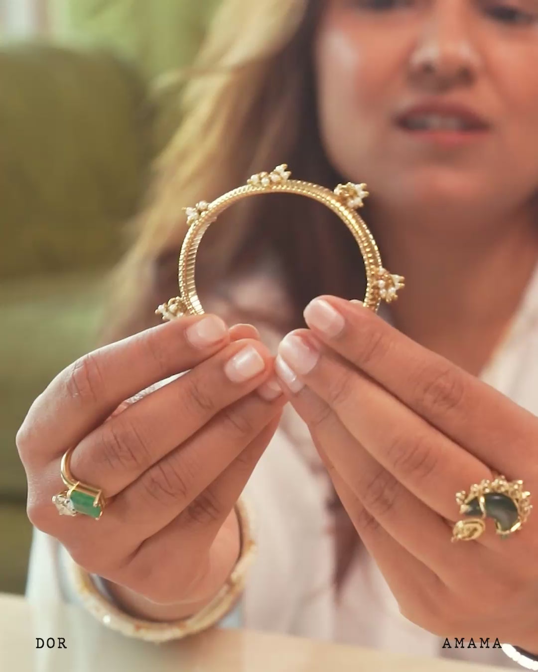 Gold bracelet with decorative elements on a white background, featuring the brand 'AMAMA'.