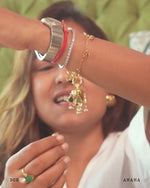 Gold bracelet with a pendant worn on a wrist, with a blurred background